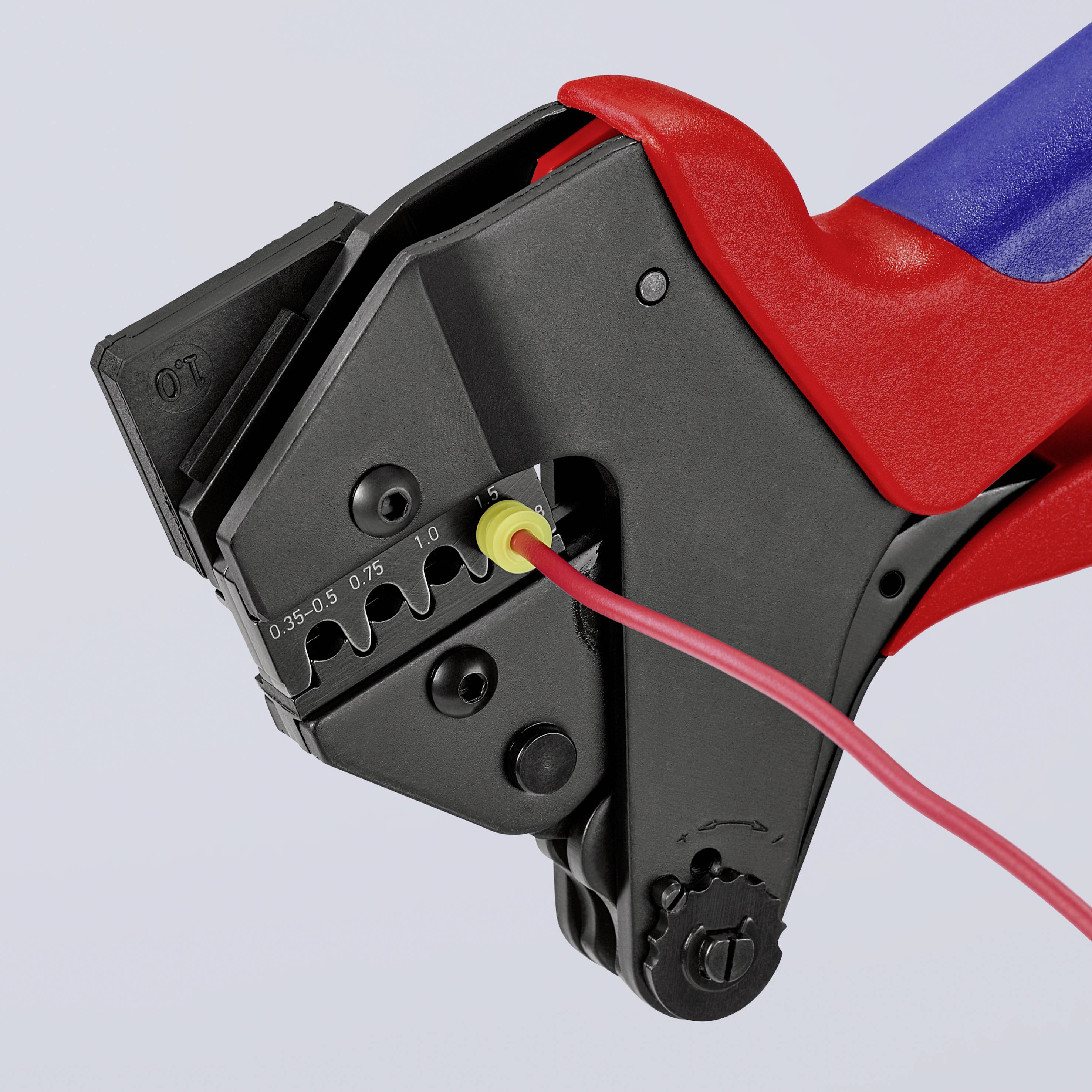 A red pair of pliers with blue handles secures a yellow wire in its cutting blades. The pliers have precision scale markings.