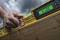 A hand is holding a yellow spirit level with a digital display reading -31.00, over a wooden beam, against a cloudy sky.