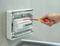 'A hand is adjusting the switch of an electrical fuse in a fuse box with a screwdriver.'