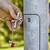 A hand is holding a spanner and removing a securing bolt from a grey metal rod in an outdoor environment.