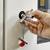 A hand turns a key in a lock. A red keyring hangs from the key, which is inserted in a door.