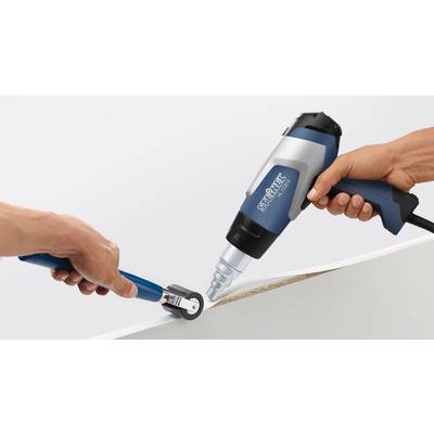 A person is using a hot air blower and a squeegee to attach edge banding to a board.