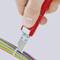 A hand is holding a red tool that cuts cables with coloured insulation.