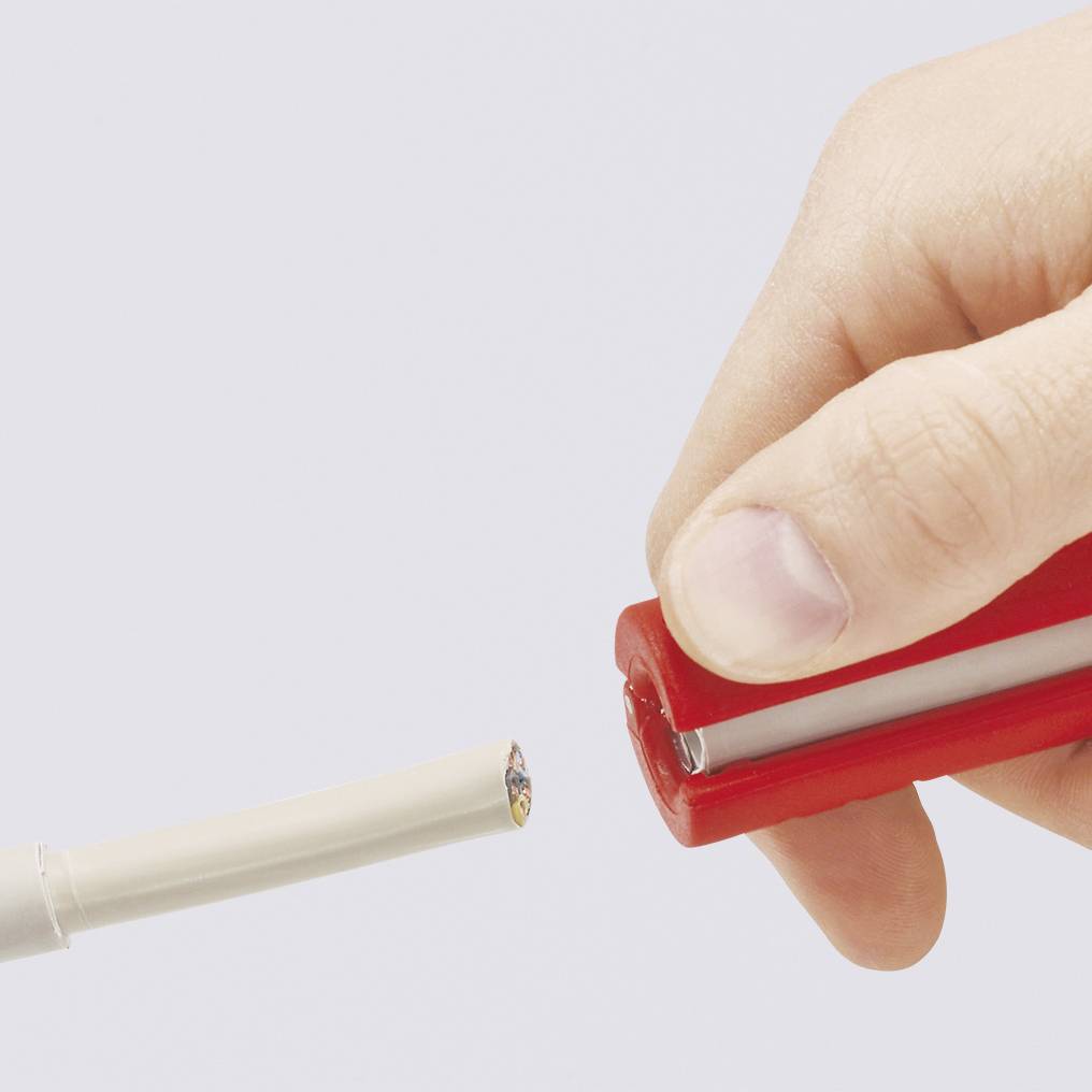A hand is holding a red cable cutter and cutting a white cable that comes in from the left edge of the image.