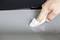 A hand wipes a grey, smooth surface with a white cloth, removing dust.