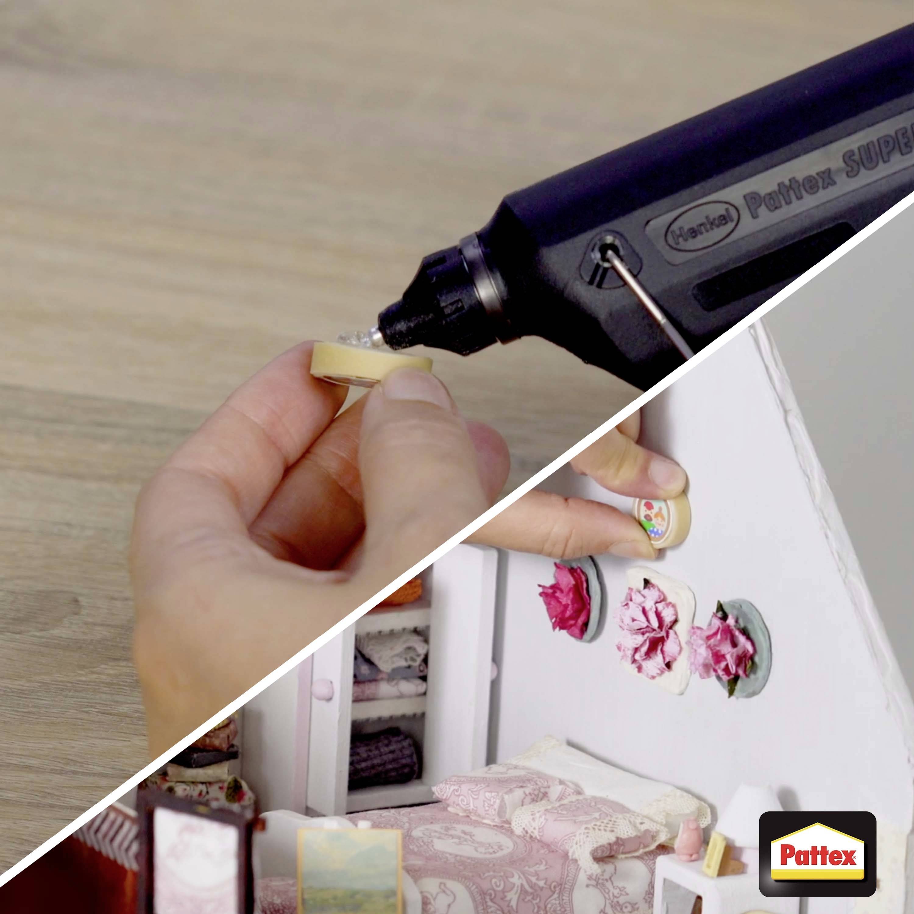 'A person gluing a tiny beige cloth piece onto a dollhouse wall, using a Pattex glue gun, with a close-up on their hands and the precise application.'