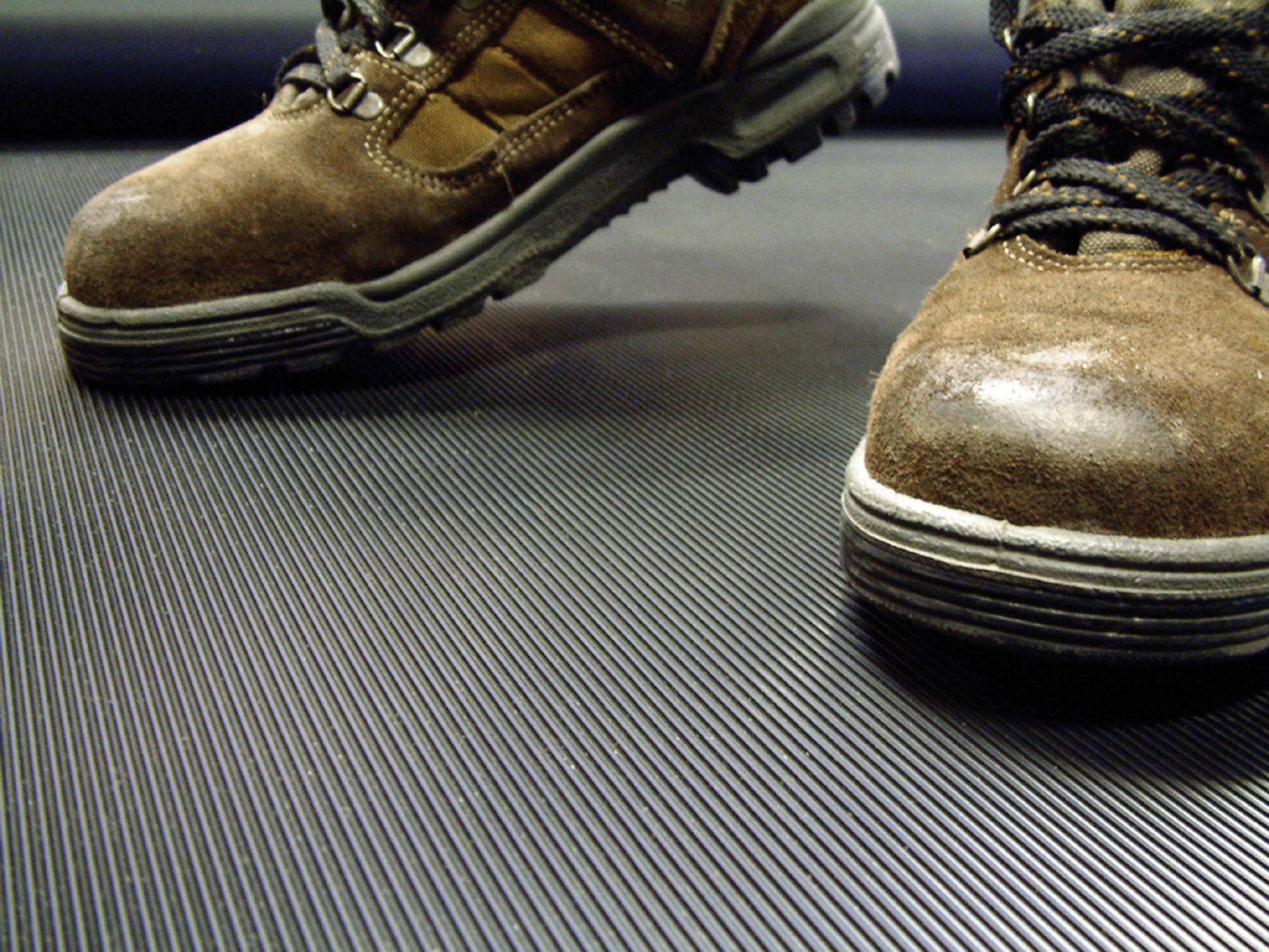 A pair of brown hiking boots stands on a ribbed, dark surface.