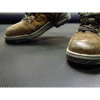A pair of brown hiking boots stands on a ribbed, dark surface.