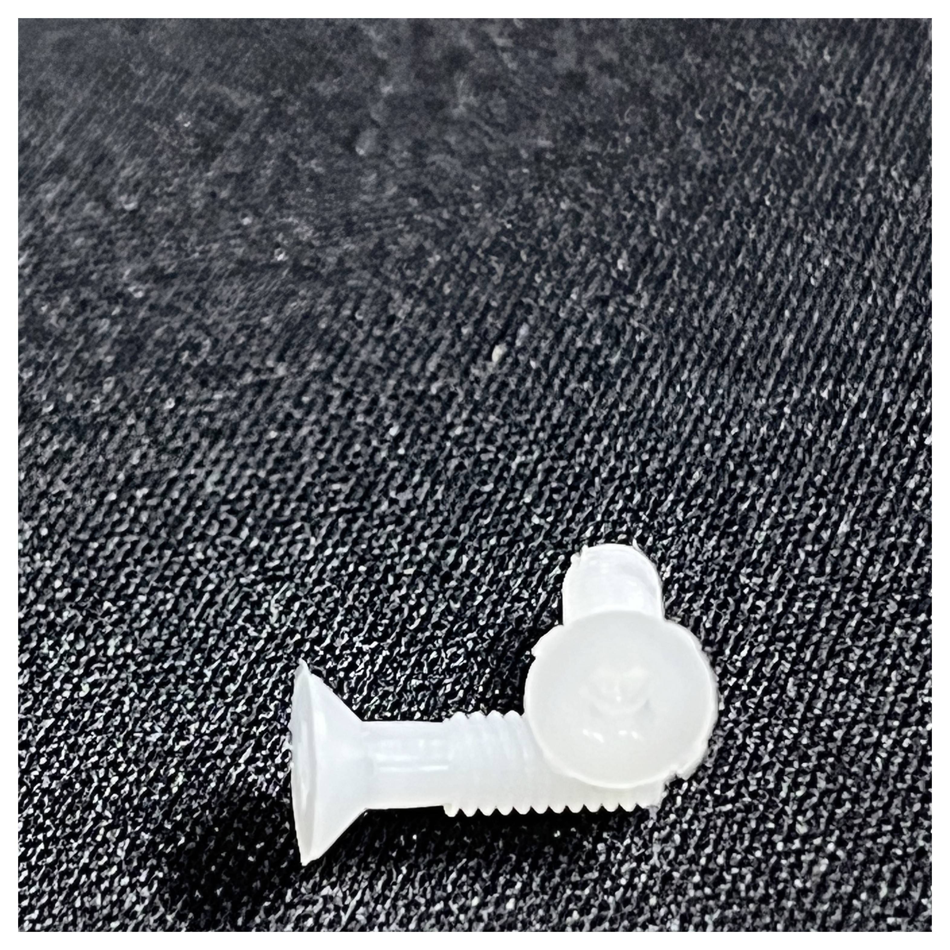 Two white plastic screws lie on a textured black surface, positioned at a right angle to each other.