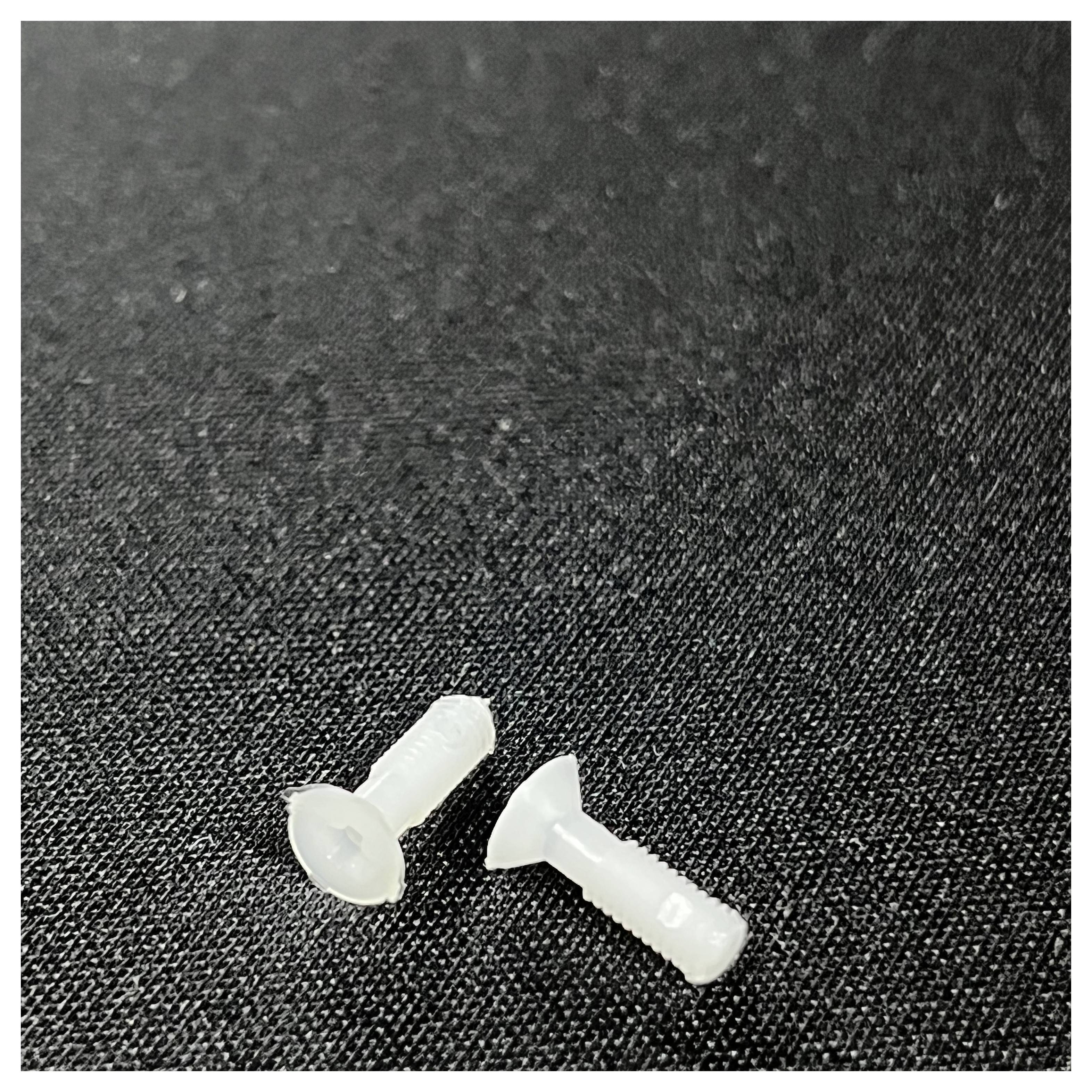 Two small, translucent screws on a black textured surface.