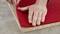 A hand is placing a red felt piece onto a chipboard, likely for a craft or construction project.
