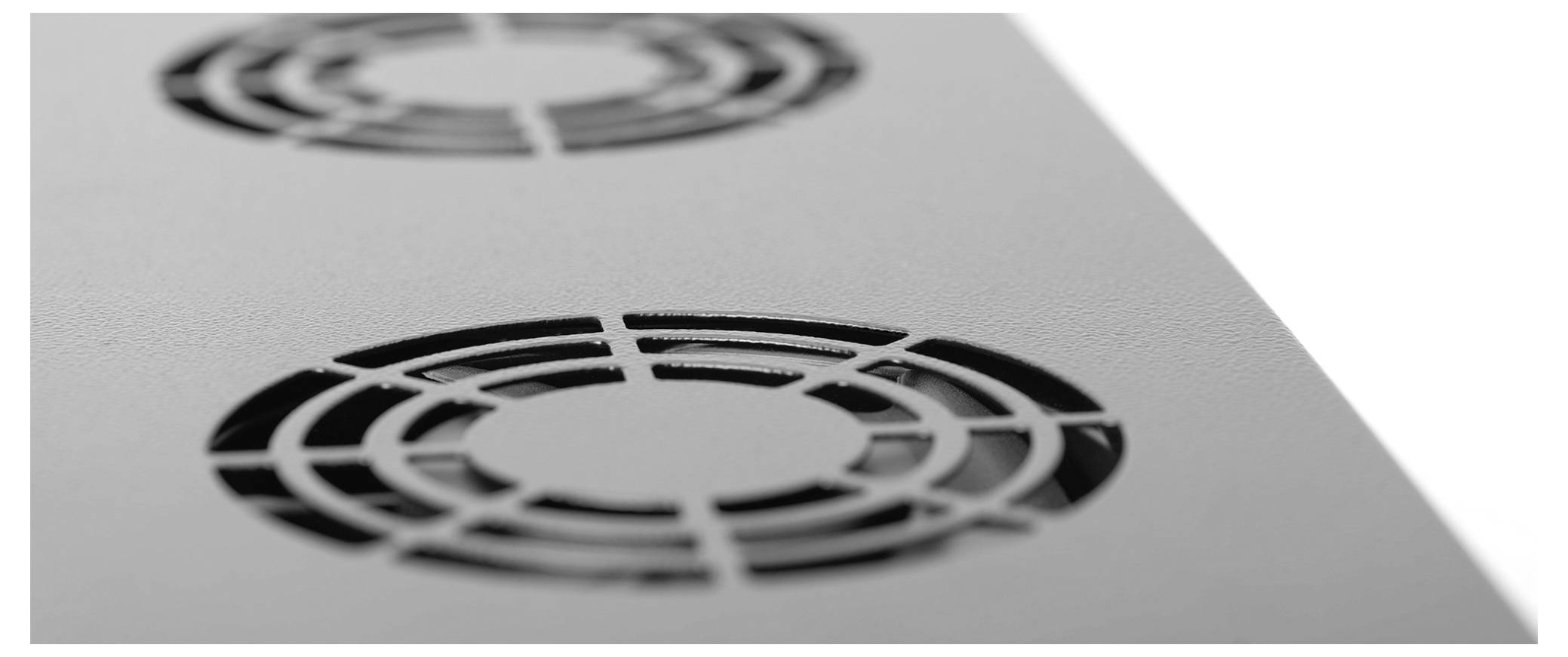 'Close-up of two circular air vents on a white surface, with a grid pattern, suggesting ventilation equipment or a cooling system.'