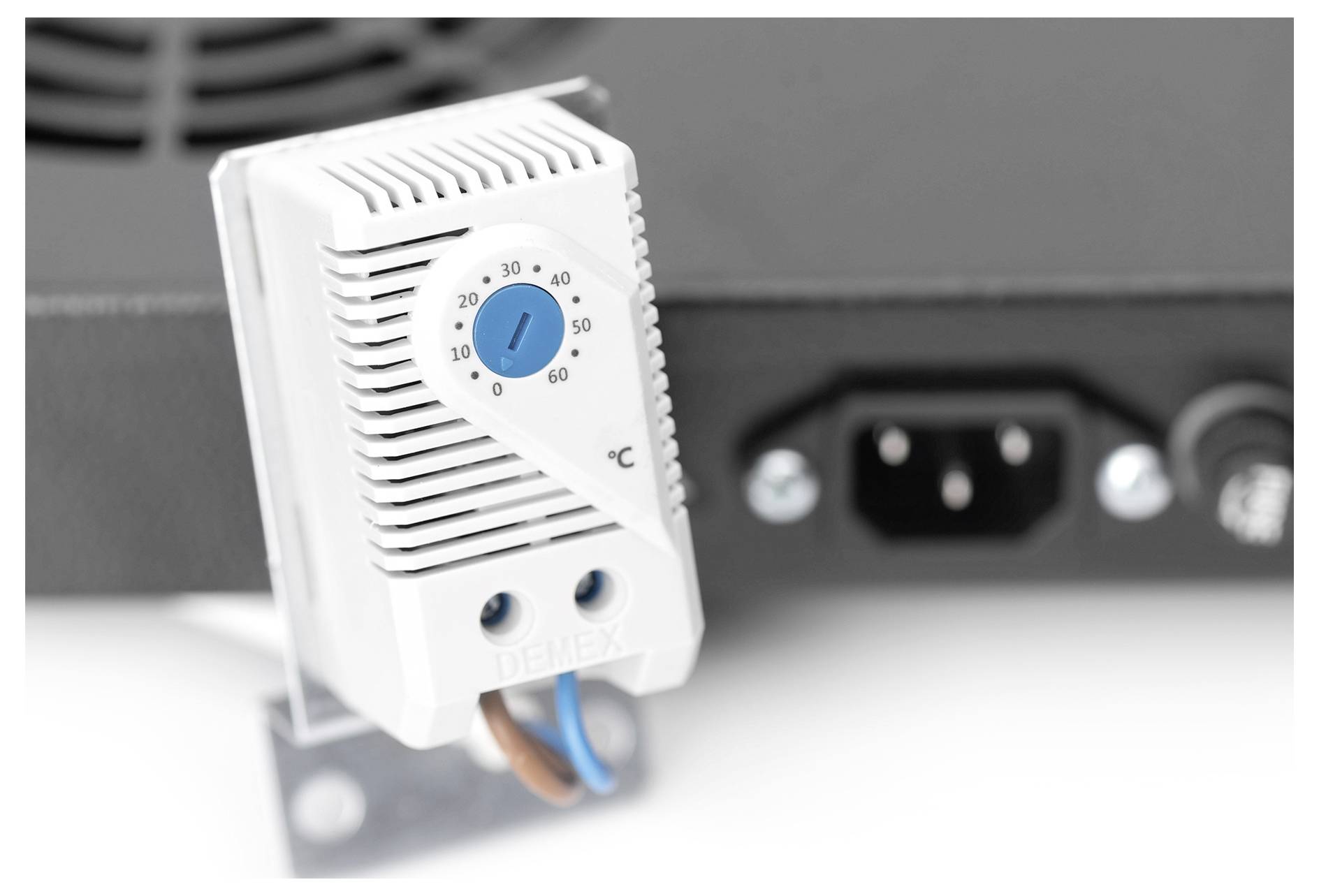 A white temperature control device with a rotary dial is set at approximately 60°C, attached to equipment, showing power connections.