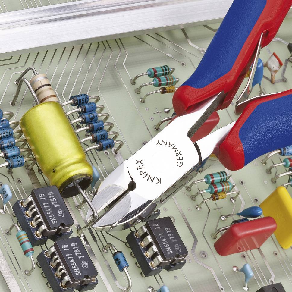 An electronic circuit board with resistors, ICs and capacitors. A red pair of pliers carefully grasps a yellowish resistor.