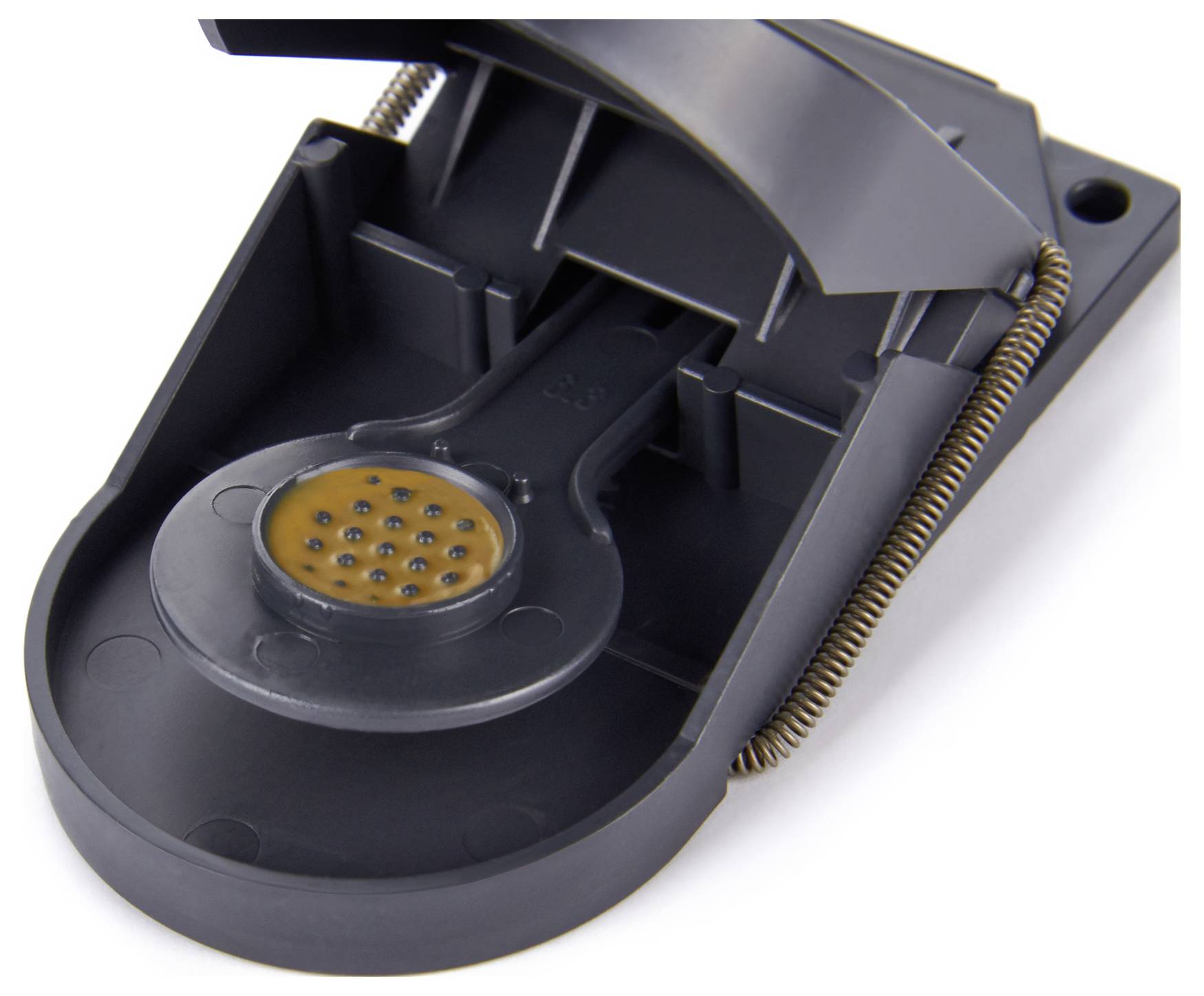 A black mousetrap device with a circular trigger plate, featuring a textured metal pad and a spring mechanism for activation.