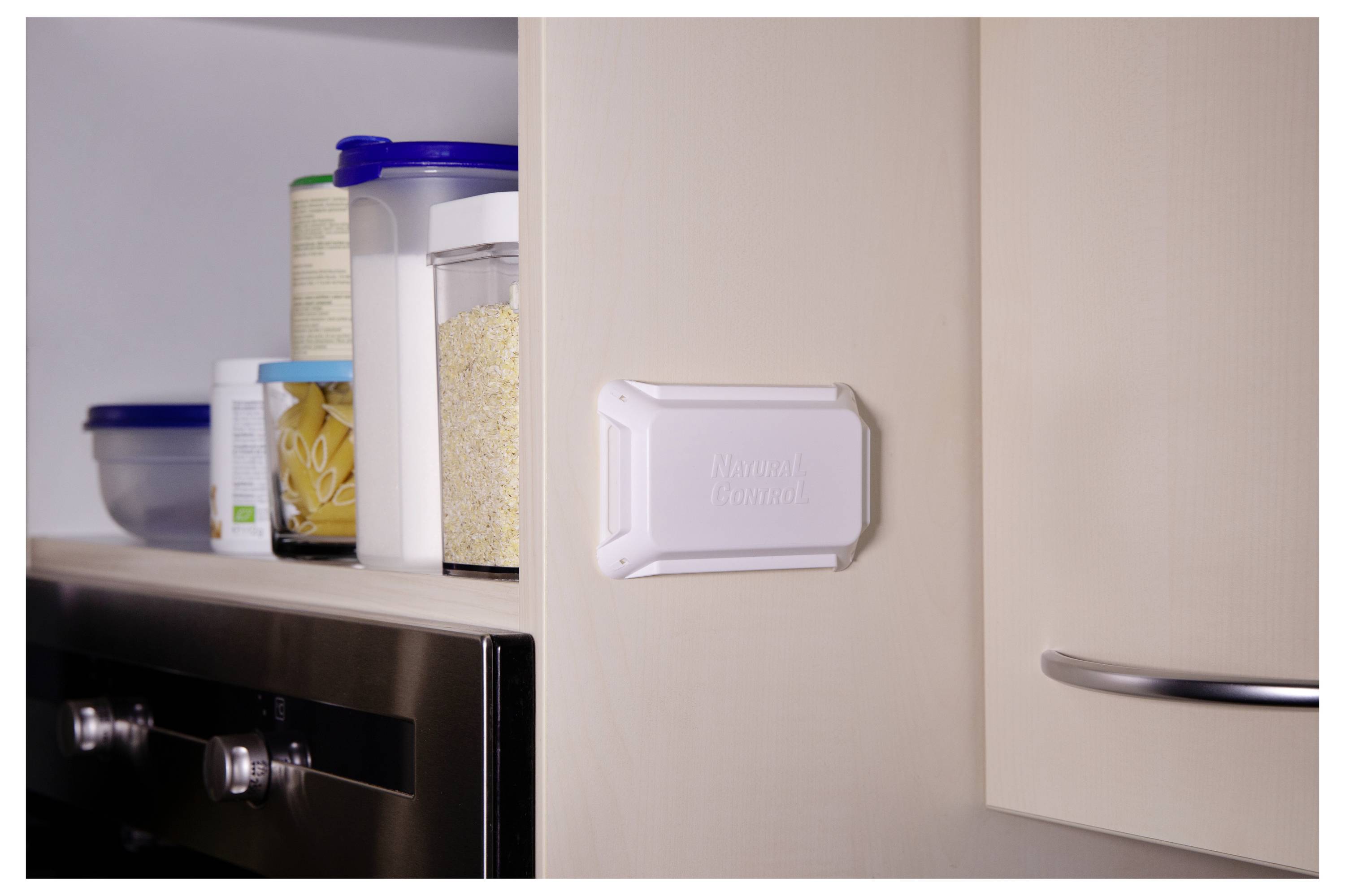 A pantry shelf with various food containers next to an oven; a white device labeled 'Meural Canvas' is attached to the cabinet.