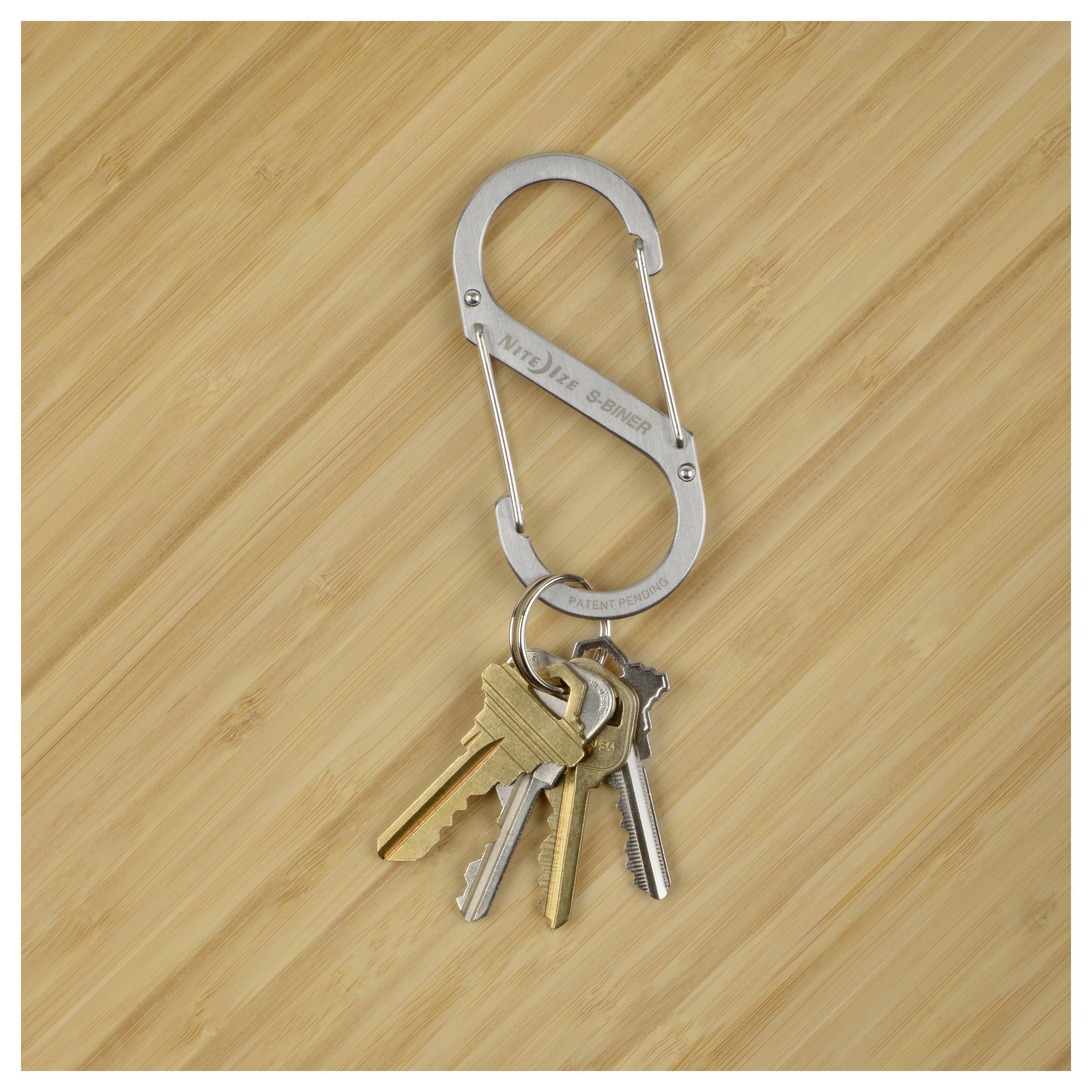 A set of keys with different shapes and sizes attached to a metal carabiner, placed on a wooden surface.
