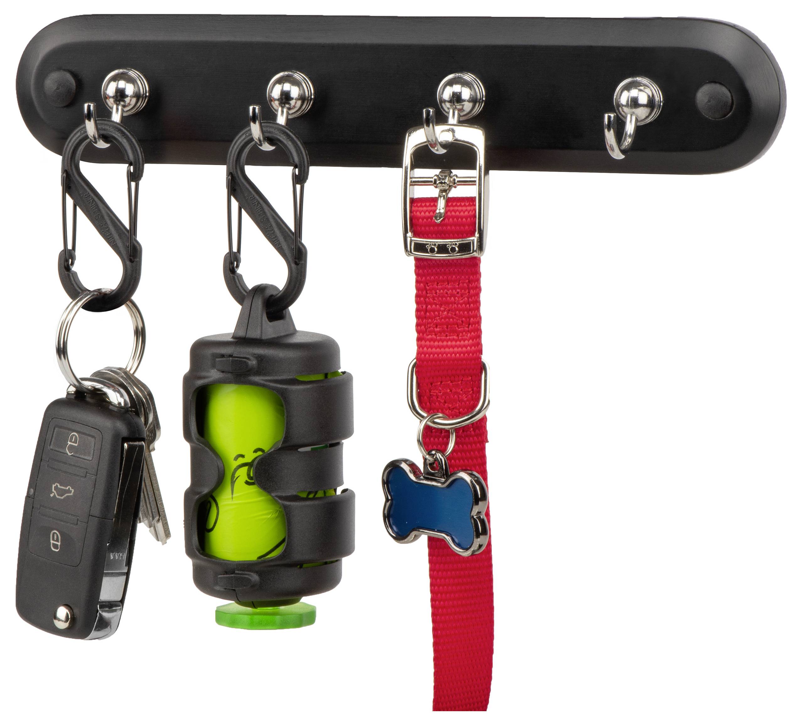 A black wall rack holds a car key, a green waste bag dispenser, and a red dog leash with a blue bone-shaped tag.