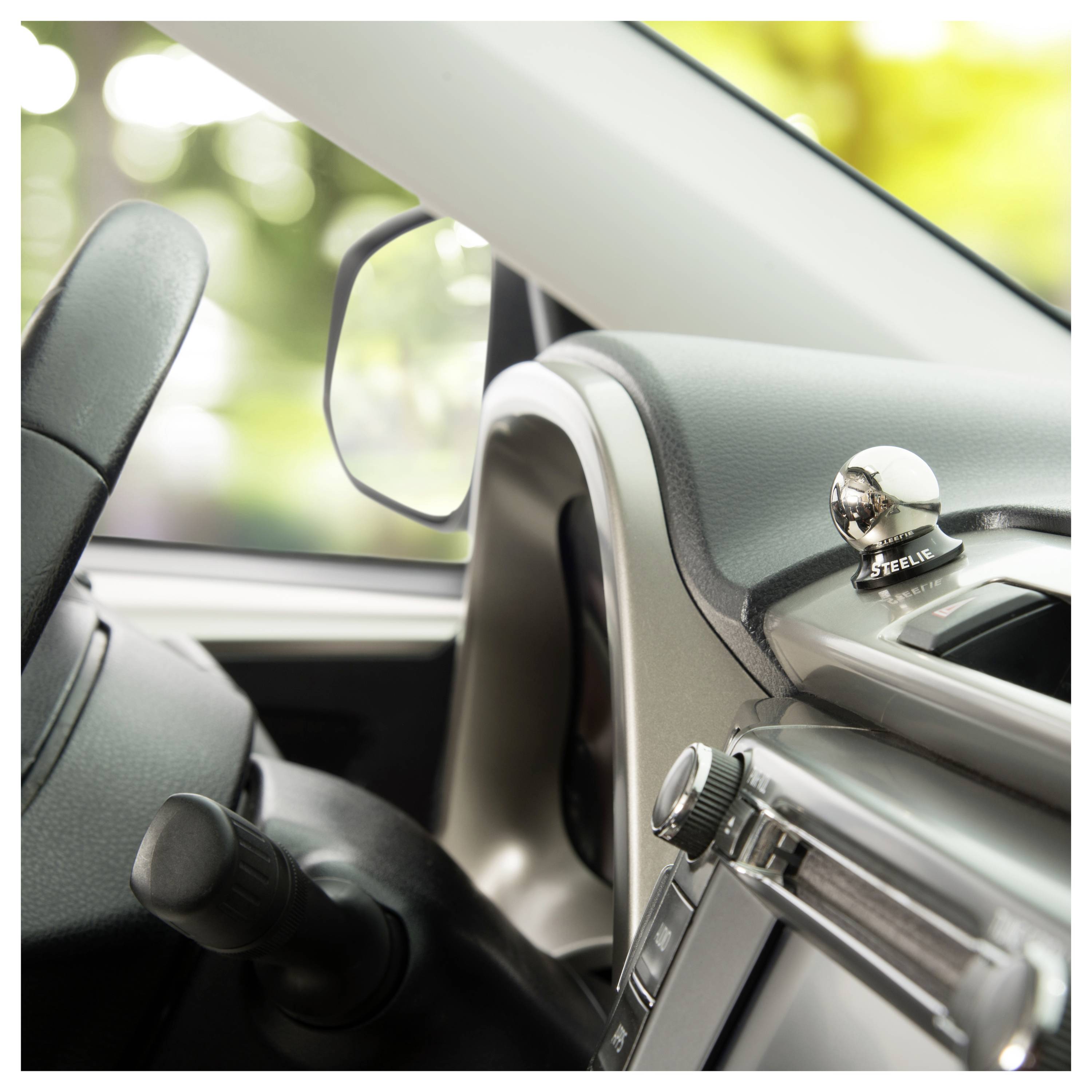 A car interior showing a steering wheel alongside a dashboard featuring a device with the label 'Steelie' used for mounting accessories.