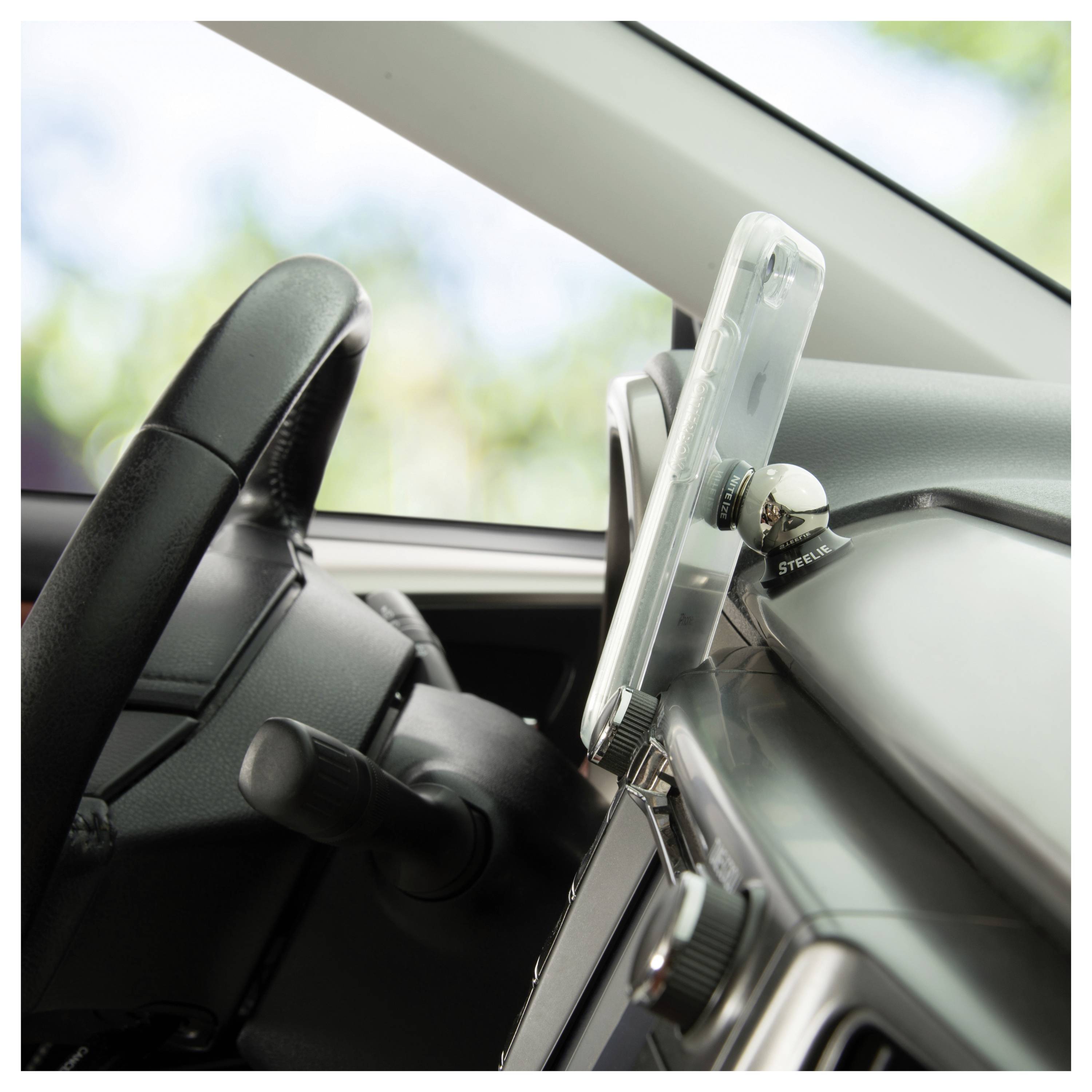 A smartphone mounted on a car dashboard, showing a driver's view with steering wheel and windshield visible.