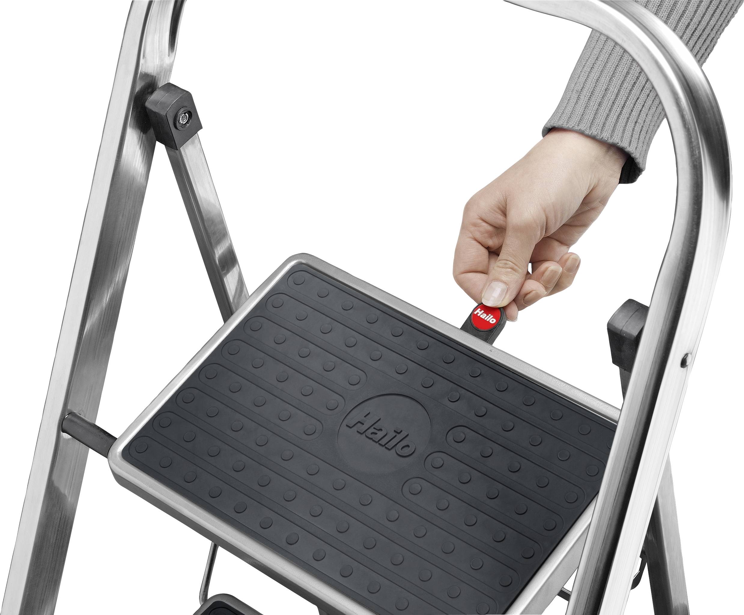 A hand pulls a red lever on the black tread of a metal stepladder. The tread displays the word 'Hello'.