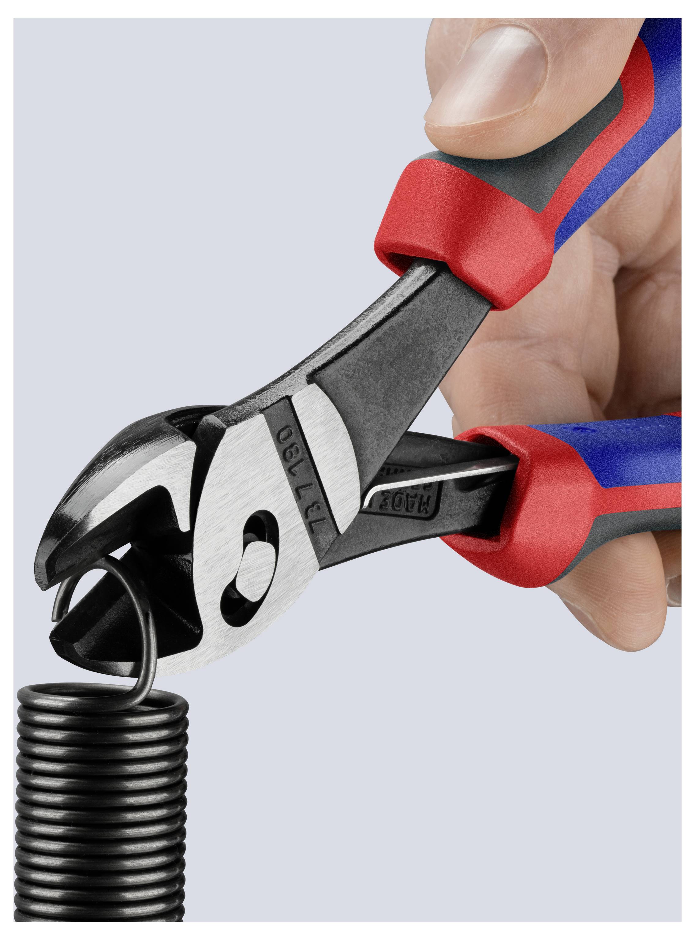 A hand using red and black pliers cuts a coil of black wire against a light gray background.