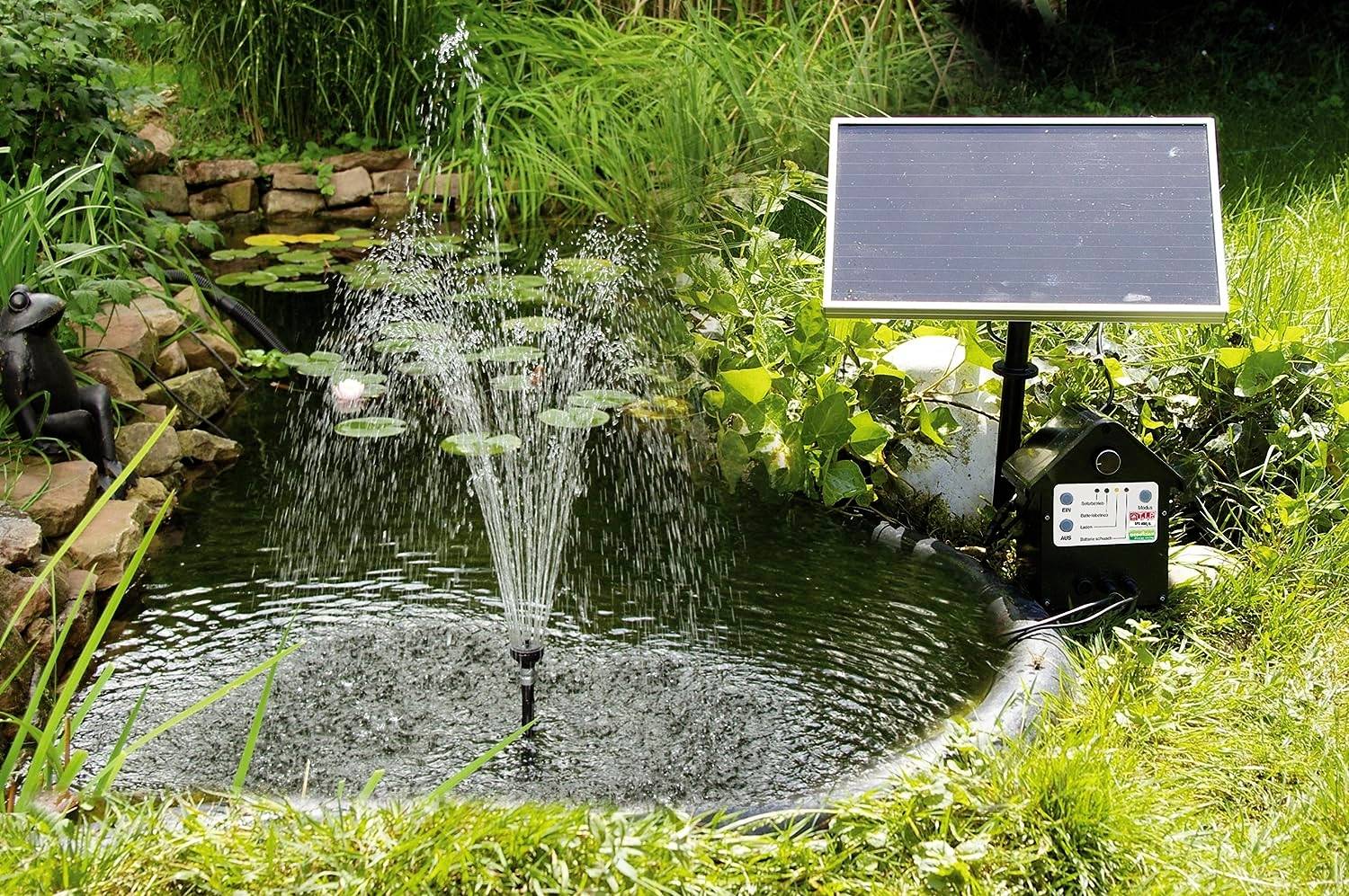 A garden pond with an active water fountain powered by a solar panel. The panel is situated on a grassy area beside the pond.
