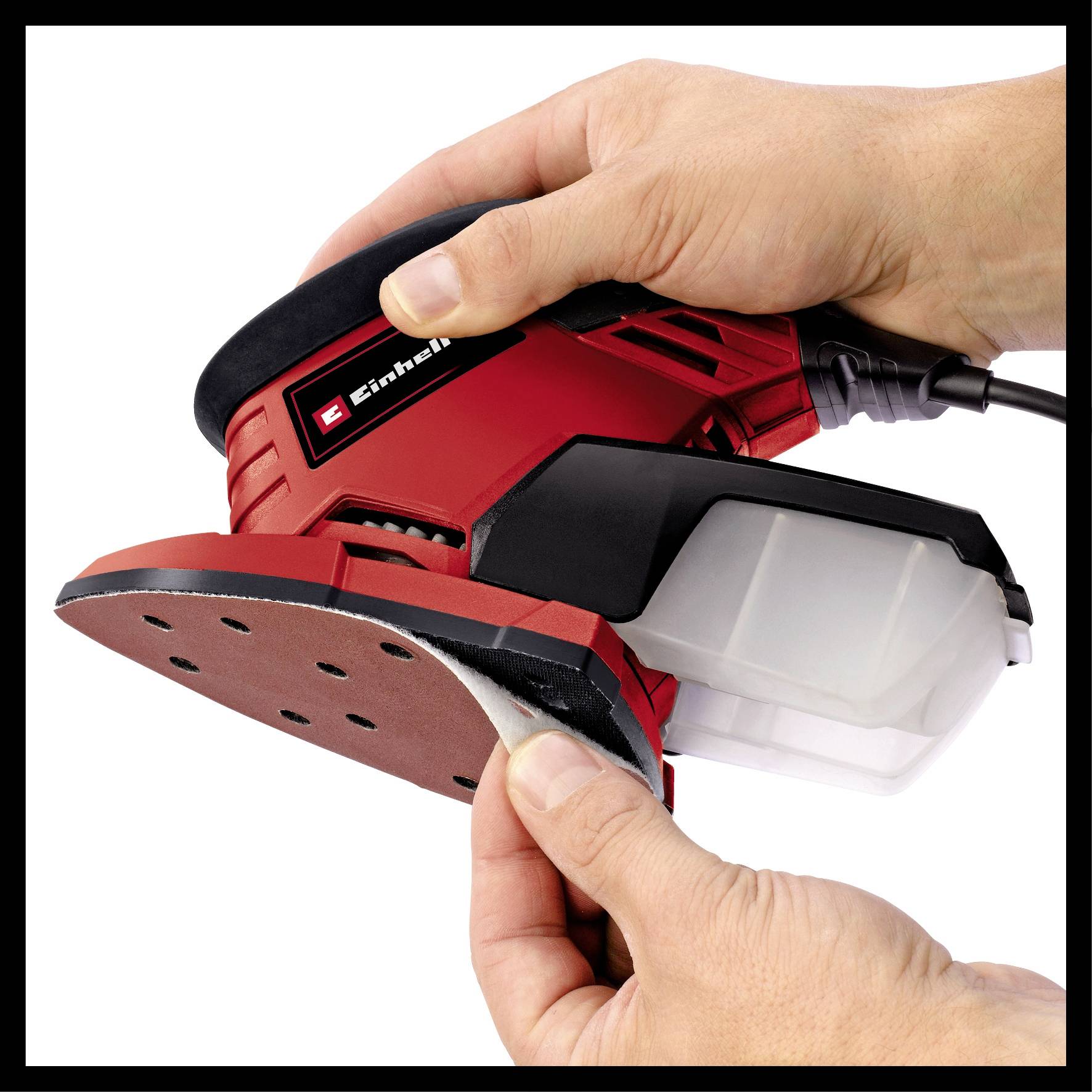 Two hands are holding a red electric sander while sandpaper is being changed. A dust container is attached to the device.