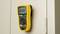 A yellow multimeter is attached to a grey cabinet. The display shows '0.000 V'. The device is in the OFF mode.