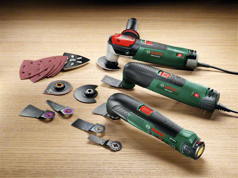 Various Bosch tools and accessories on a wooden surface, including two multi-functional power tools with attachments and sanding sheets.