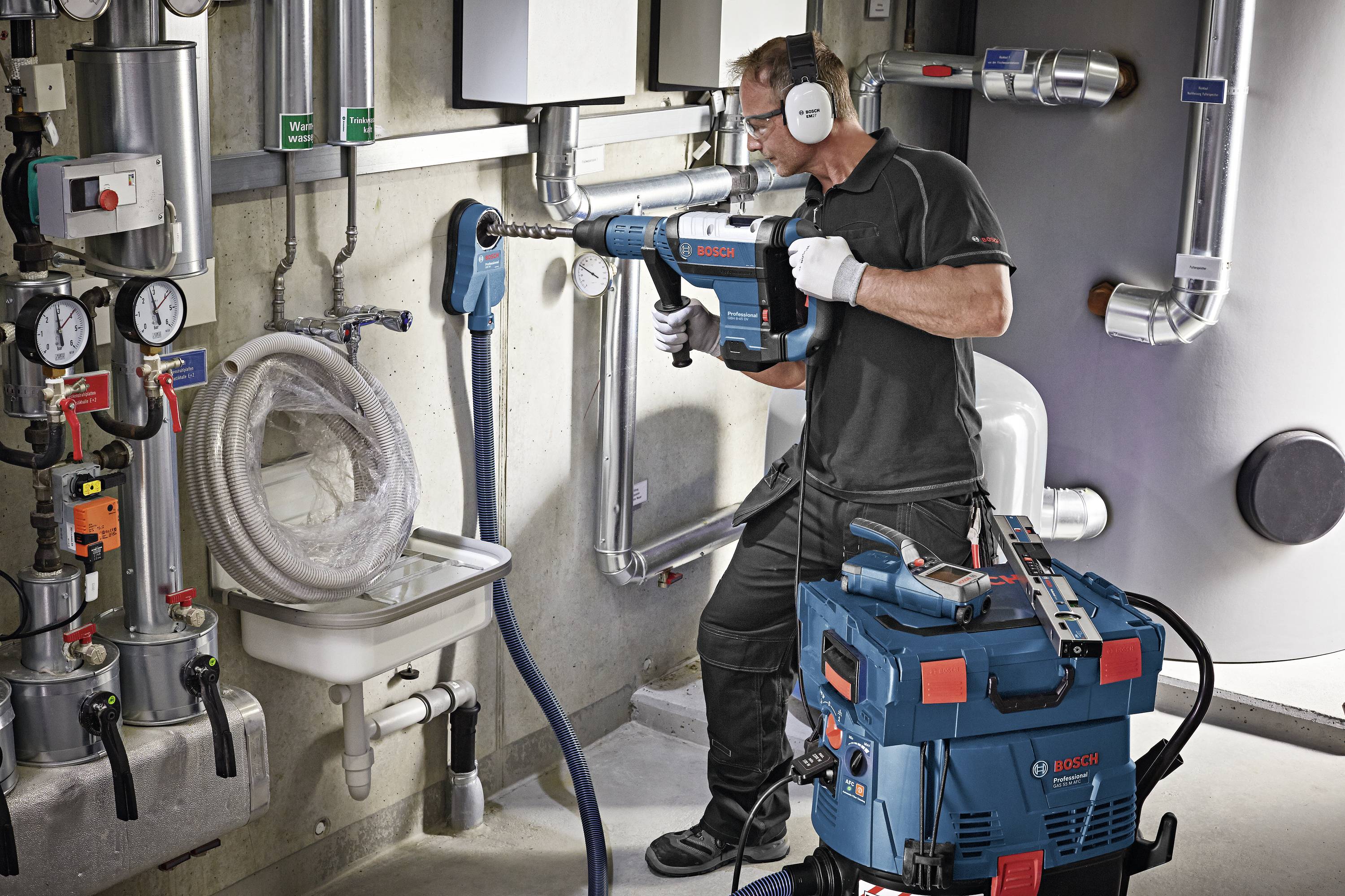 A technician in a workshop is using a Bosch electric tool. Pipes and measuring instruments can be seen in the background.