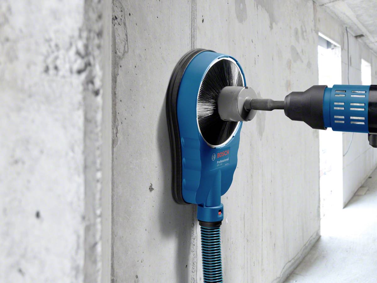Drilling into a concrete wall with a dust extraction system. A drill with a dust extraction hood minimises dust and dirt during drilling.