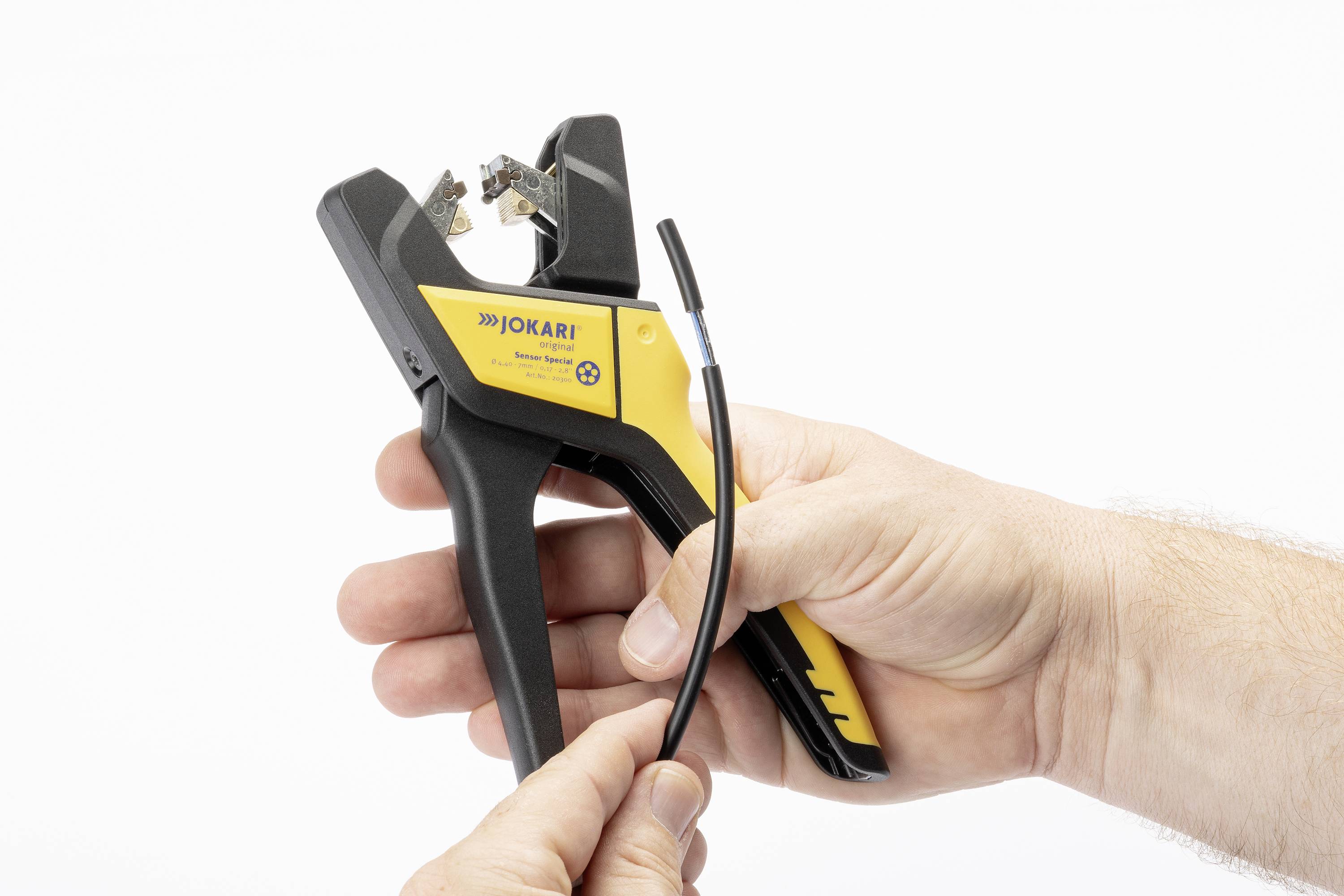 Two hands are holding a yellow and black automatic wire stripper. A cable is being stripped to prepare it.