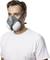A man is wearing a respirator mask with filters on both sides, dressed in a white T-shirt.