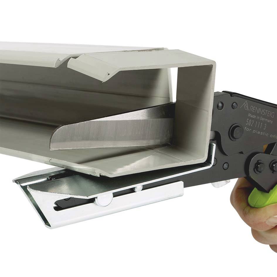 A hand is holding a tool that is cutting a rectangular metal plate.