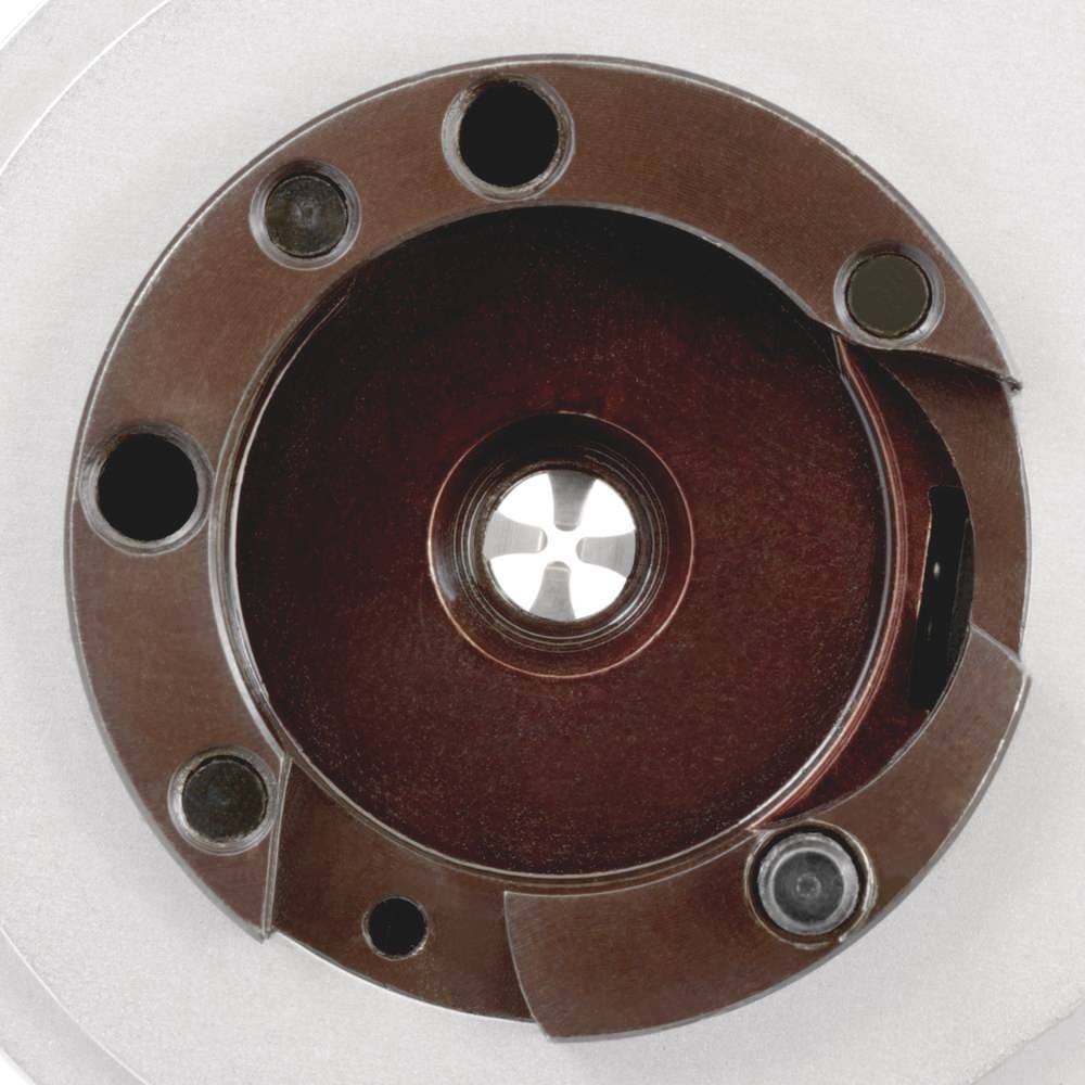 'Close-up of a metal bearing with four holes and a central aperture, mounted in a circular housing, on a grey background.'