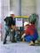 Two construction workers wearing white hard hats are installing a pre-wall element for a toilet in an unfinished building. One is checking the frame, while the other is crouching on the floor.