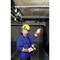 A technician in protective clothing is measuring the electrical cables on the ceiling in a basement area.