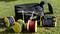 A black toolbox, three cable reels with colourful cables, and an electronic measuring device are lying on a meadow.