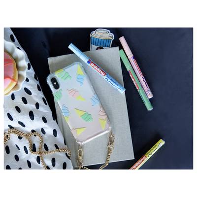Flat lay of a phone with ice-cream case on a notebook, surrounded by colorful markers and a polka-dot cloth on a dark background.
