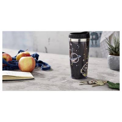 Travel mug with space-themed design on a table beside apples, a notebook, and keys, suggesting a morning departure or packed lunch scene.
