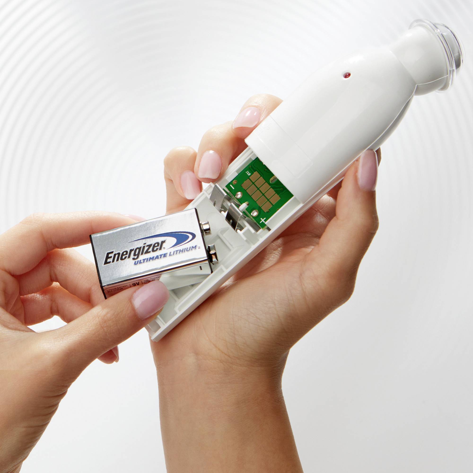 A hand is inserting an 'Energizer Ultimate Lithium' battery into an electrical device.