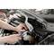 A person is repairing the engine compartment of a car with a spanner, while the bonnet is open.