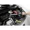 A person is using a torque wrench to tighten a bolt in the engine bay of a car.