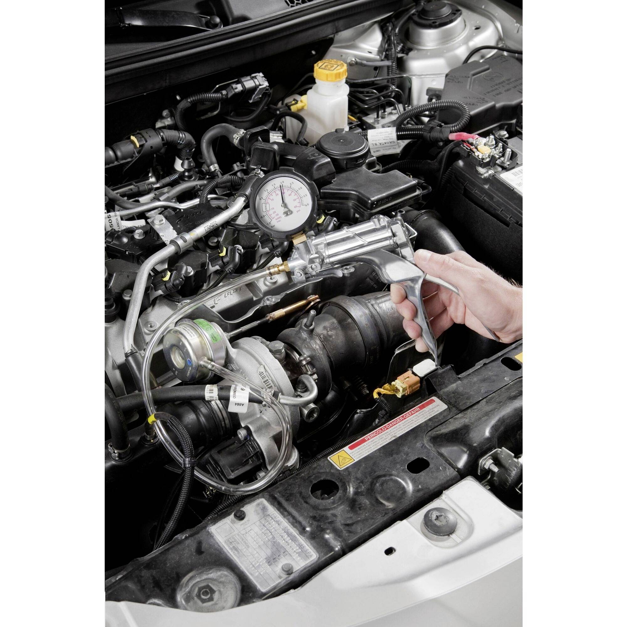 A mechanic is conducting a compression test on a car engine to check its performance. A pressure gauge is visible.