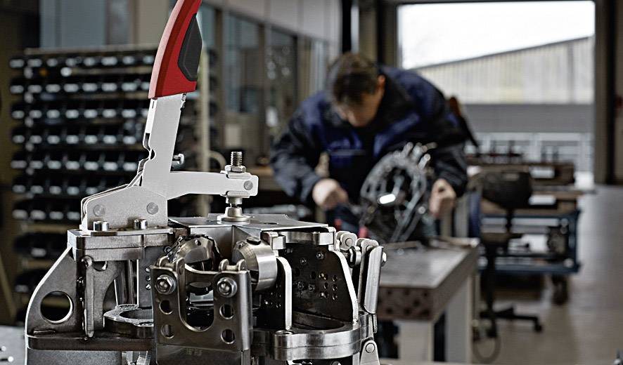 Machine in the foreground in a workshop. Craftsman in the background, out of focus. Focus on engineering work and mechanical engineering.