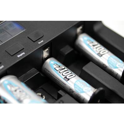 Four AA batteries are being charged in a charger. Two batteries in the foreground, one and a control display blurred in the background.