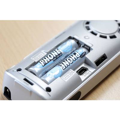 Silver remote control with two AA batteries inserted, lying on a wooden table.