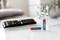 A remote control is lying on a table, next to two batteries, one lying down ('AAA Alkaline') and one standing upright.