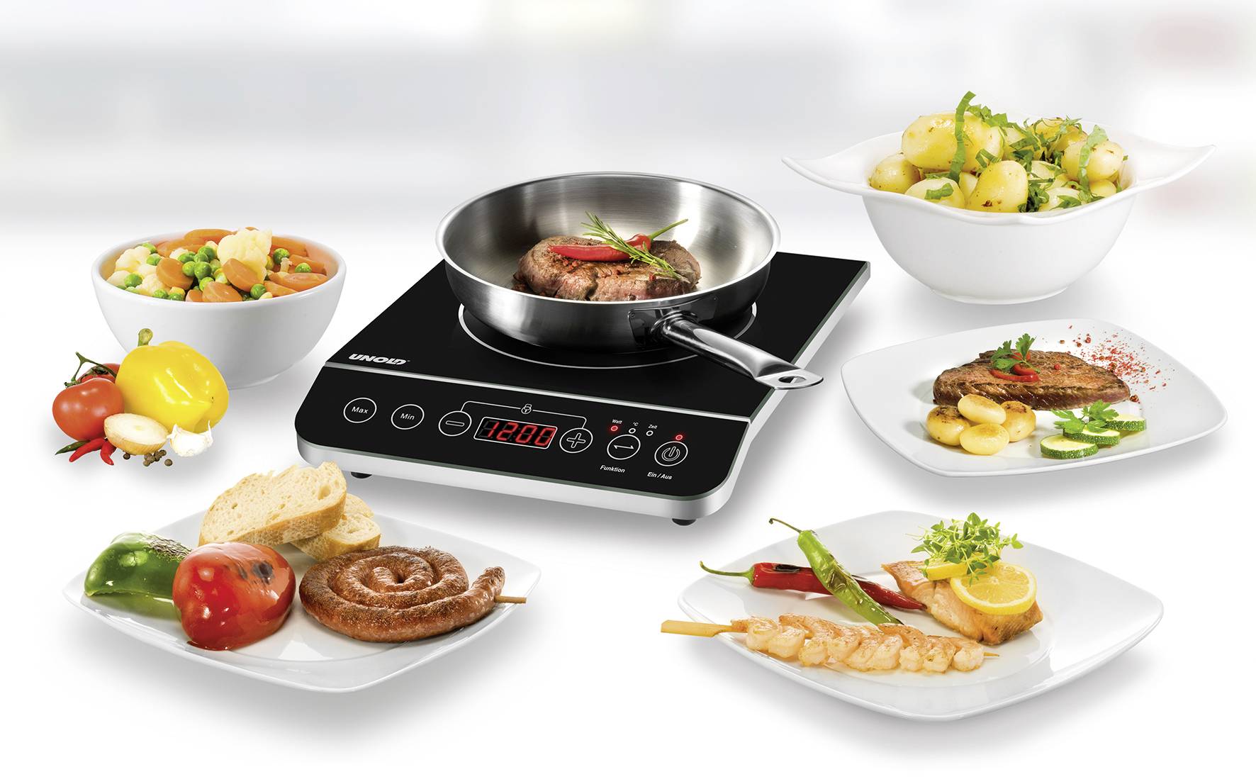 Modern hob ring with a pan, in which a steak is sizzling. Around it are plates with various dishes, including vegetables and potatoes.